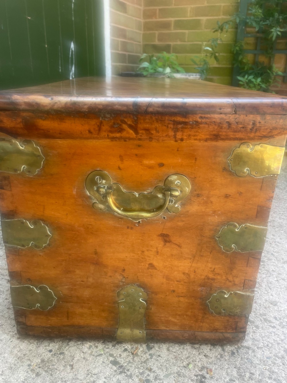 A mid-eighteenth century solid cedar trunk featuring decorative brass corner brackets, brass straps, and a central brass keyhole escutcheon. View VII