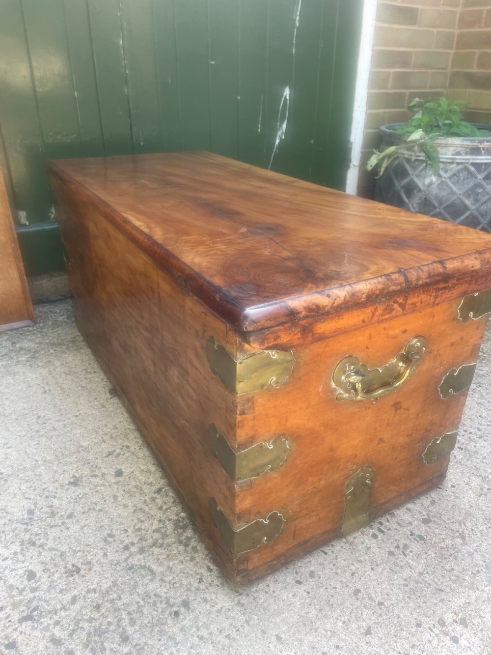 A mid-eighteenth century solid cedar trunk featuring decorative brass corner brackets, brass straps, and a central brass keyhole escutcheon. View XII
