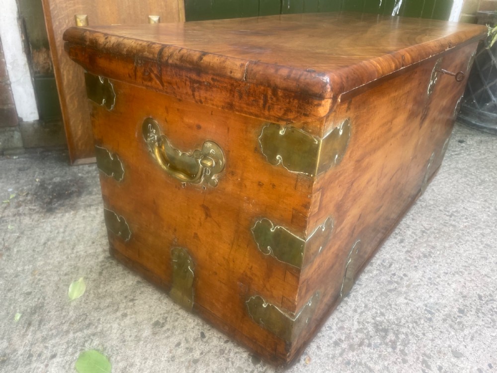 A mid-eighteenth century solid cedar trunk featuring decorative brass corner brackets, brass straps, and a central brass keyhole escutcheon. View XVII