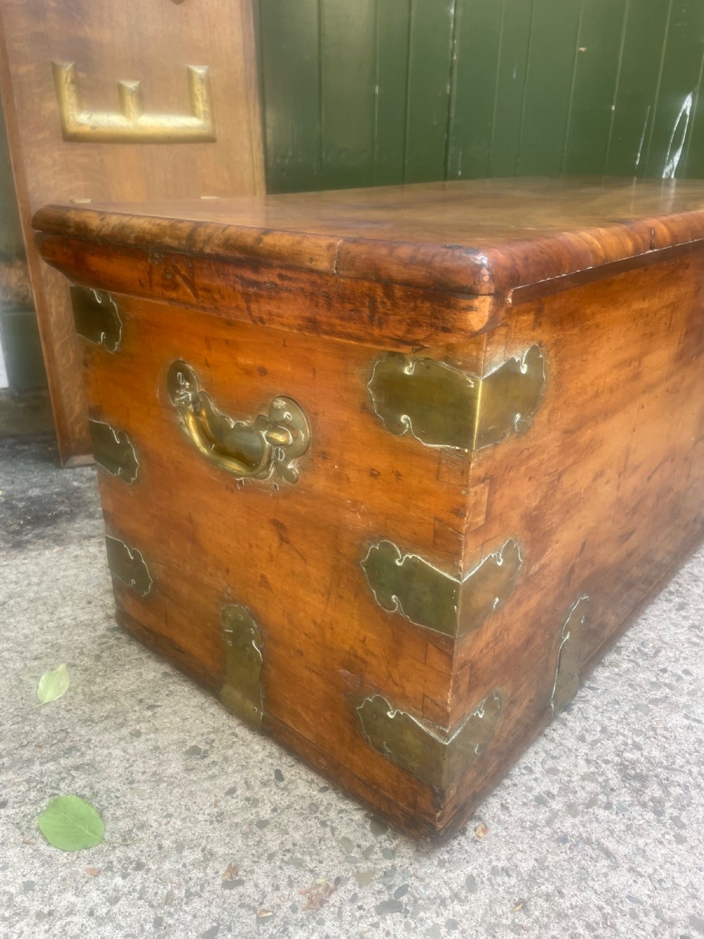 A mid-eighteenth century solid cedar trunk featuring decorative brass corner brackets, brass straps, and a central brass keyhole escutcheon. View XIX