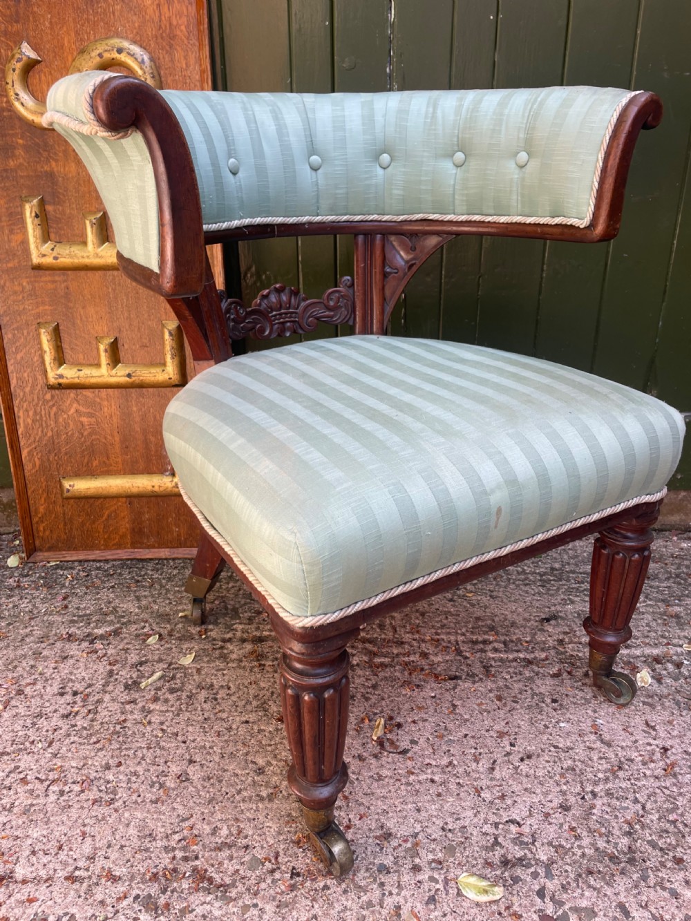 A George IV mahogany curule library armchair upholstered in pale green striped buttoned fabric with reeded front legs on brass castors. View XIII