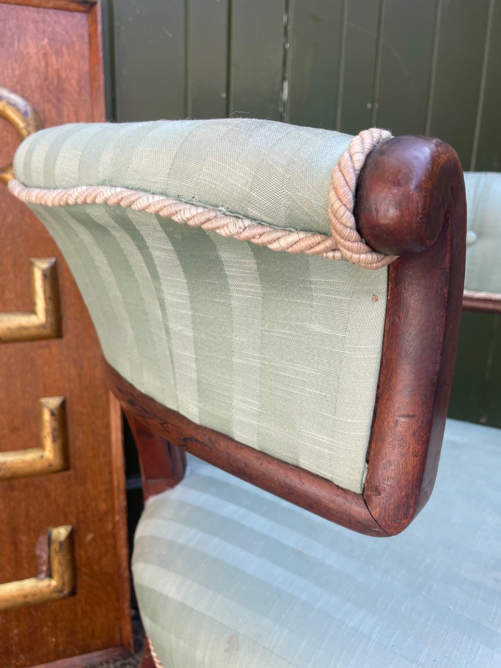 A George IV mahogany curule library armchair upholstered in pale green striped buttoned fabric with reeded front legs on brass castors. View XIV