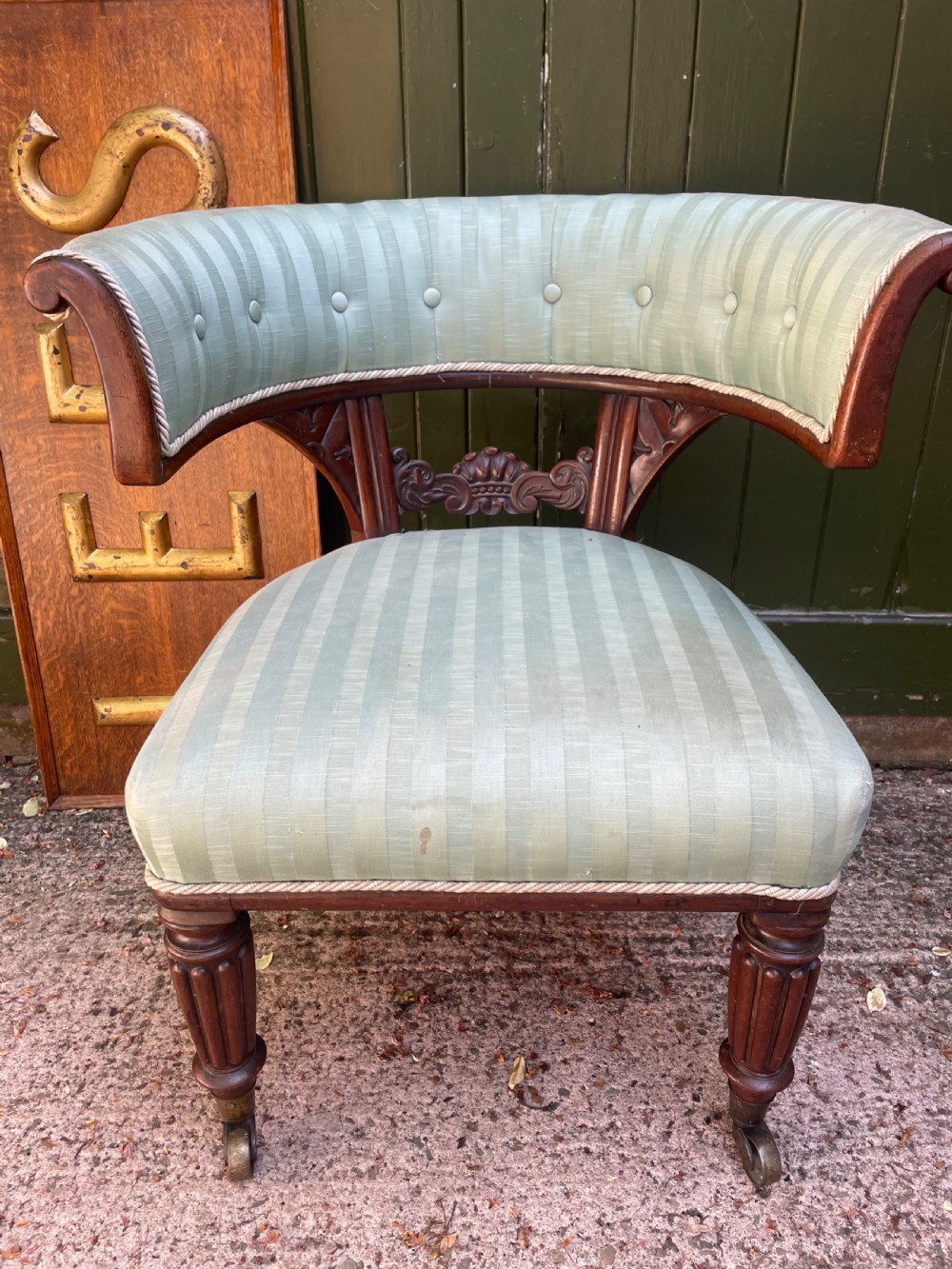 A George IV mahogany curule library armchair upholstered in pale green striped buttoned fabric with reeded front legs on brass castors. View XVII