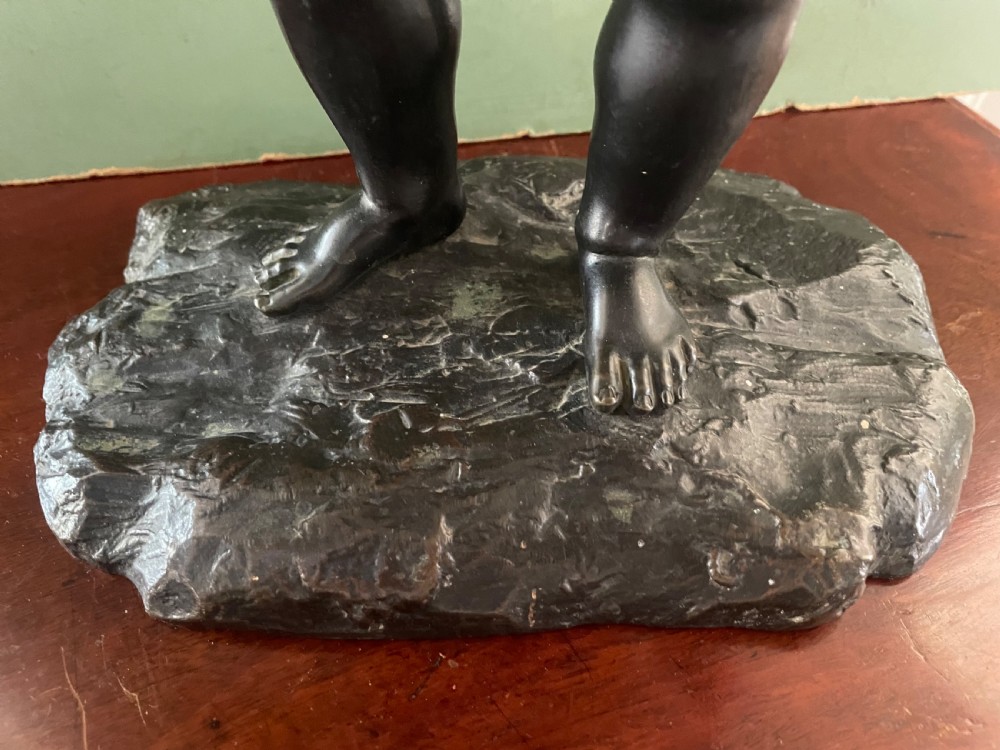 A dark patinated bronze sculpture depicting a standing putto hunter blowing a curved horn while slinging a small deer over one shoulder. View XI