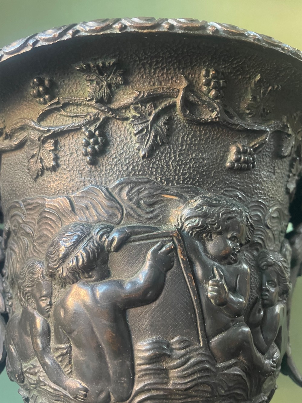 A 19th-century French dark bronze campana-shaped urn featuring relief carving of putti, satyr mask handles, and a square pedestal base. View IV