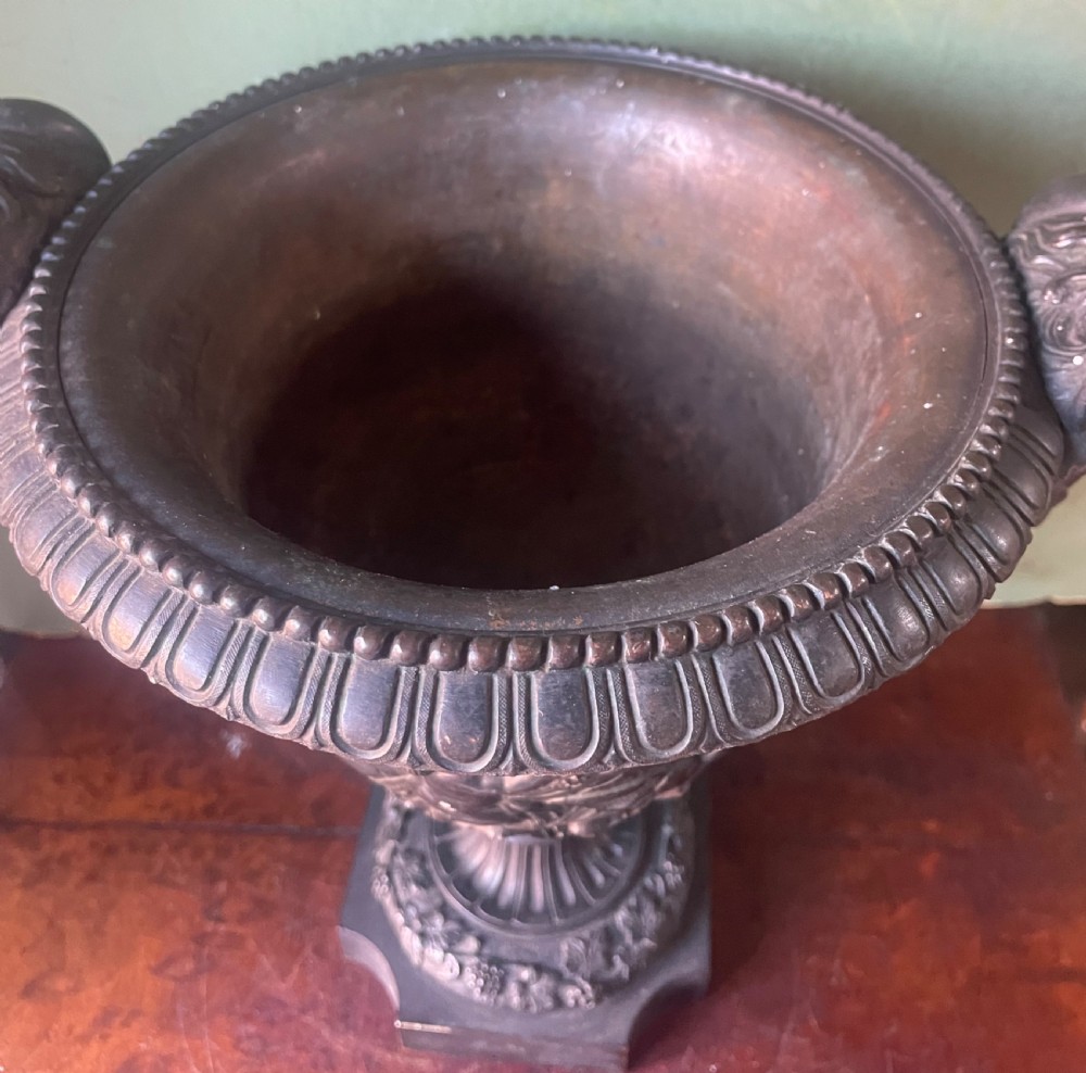 A 19th-century French dark bronze campana-shaped urn featuring relief carving of putti, satyr mask handles, and a square pedestal base. View VII