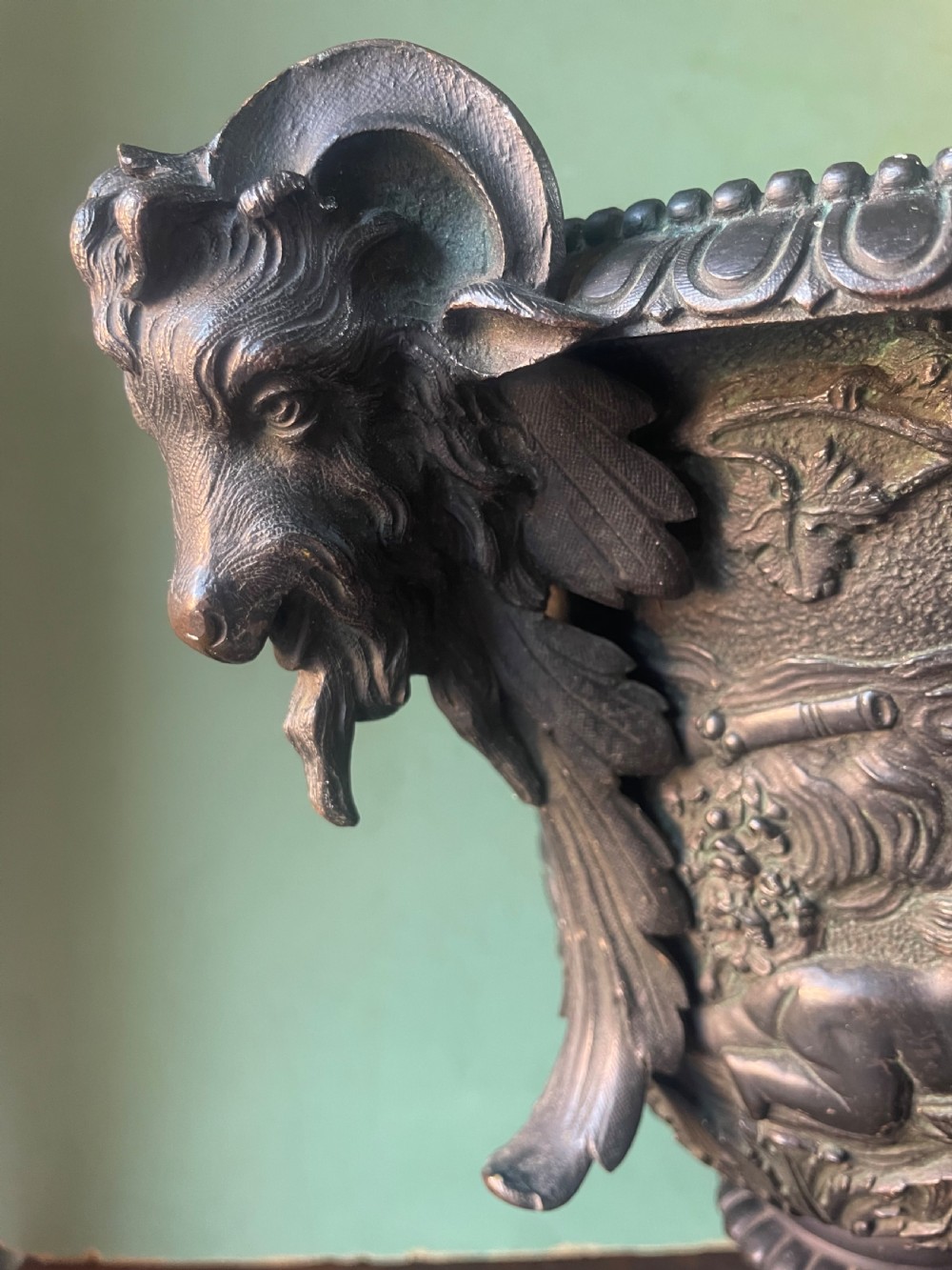 A 19th-century French dark bronze campana-shaped urn featuring relief carving of putti, satyr mask handles, and a square pedestal base. View XV