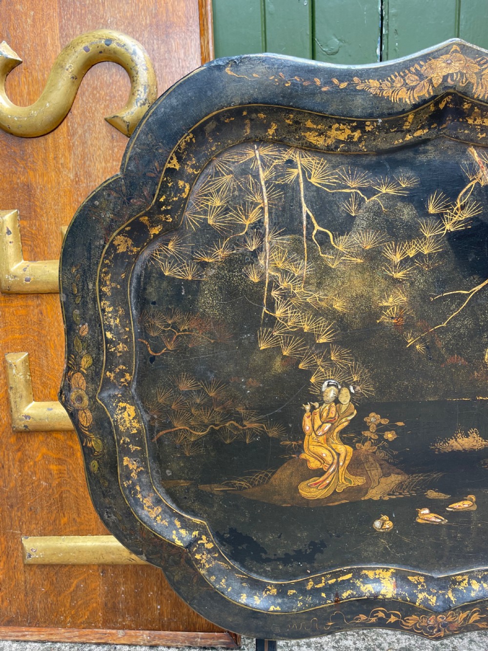 A 19th-century black lacquered papier-mache tray table featuring gilded Chinoiserie landscape decoration and scalloped edges. View II