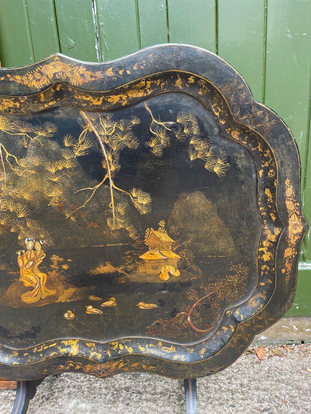 A 19th-century black lacquered papier-mache tray table featuring gilded Chinoiserie landscape decoration and scalloped edges. View III