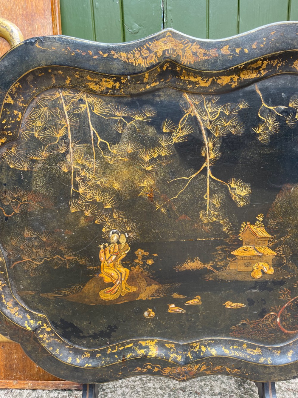 A 19th-century black lacquered papier-mache tray table featuring gilded Chinoiserie landscape decoration and scalloped edges. View IV