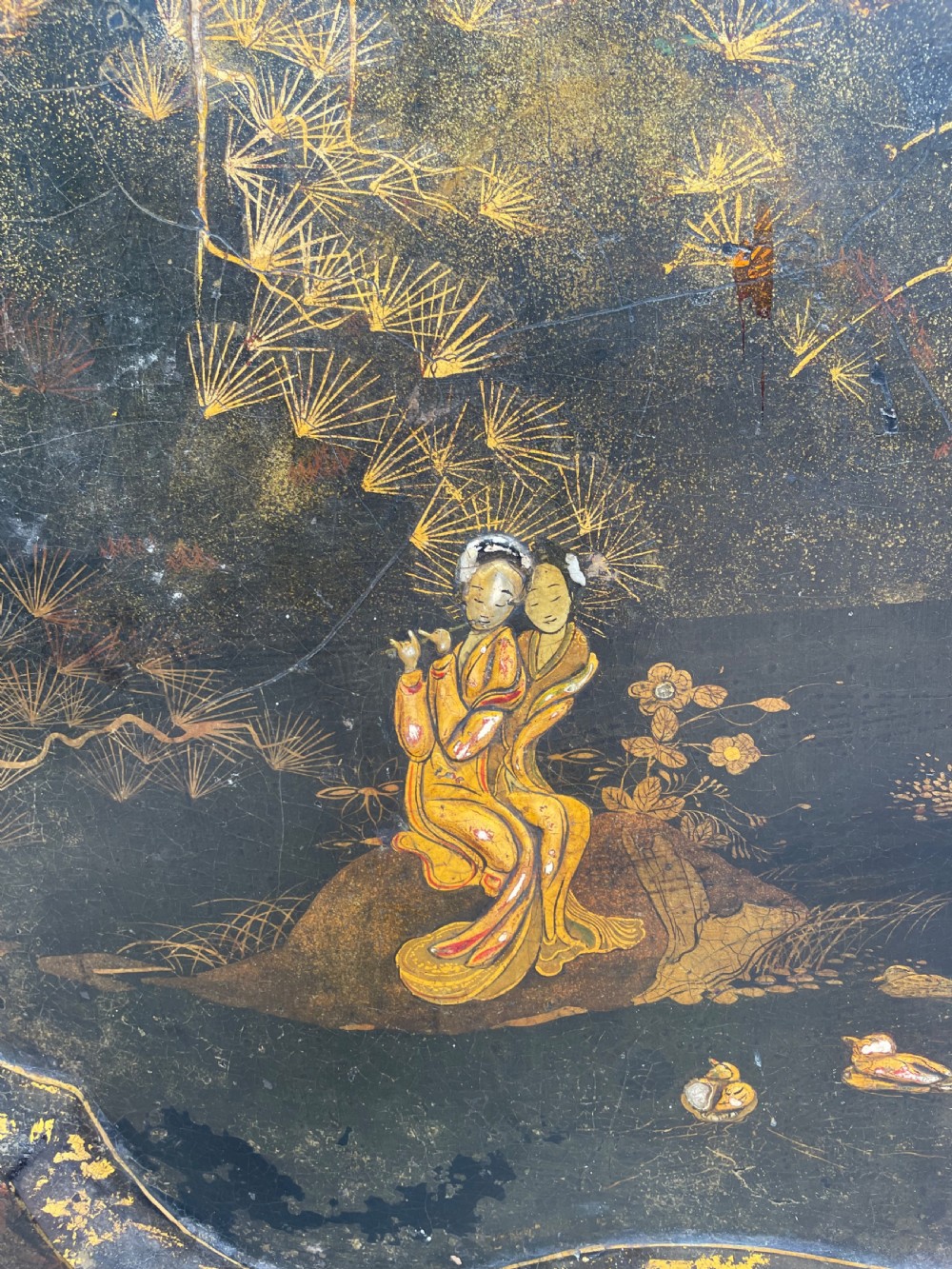 A 19th-century black lacquered papier-mache tray table featuring gilded Chinoiserie landscape decoration and scalloped edges. View V