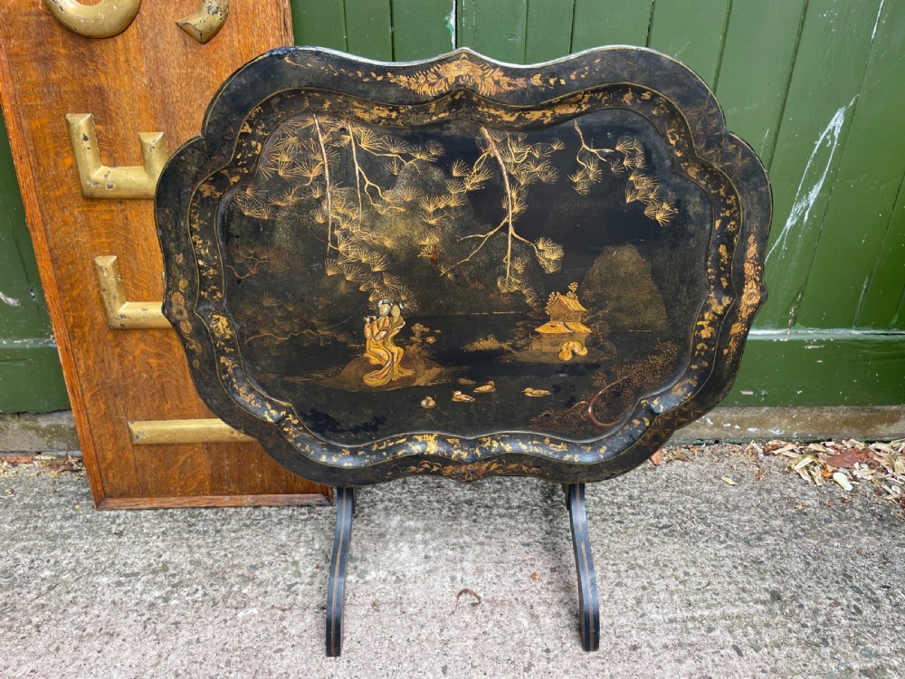 A 19th-century black lacquered papier-mache tray table featuring gilded Chinoiserie landscape decoration and scalloped edges. View VI