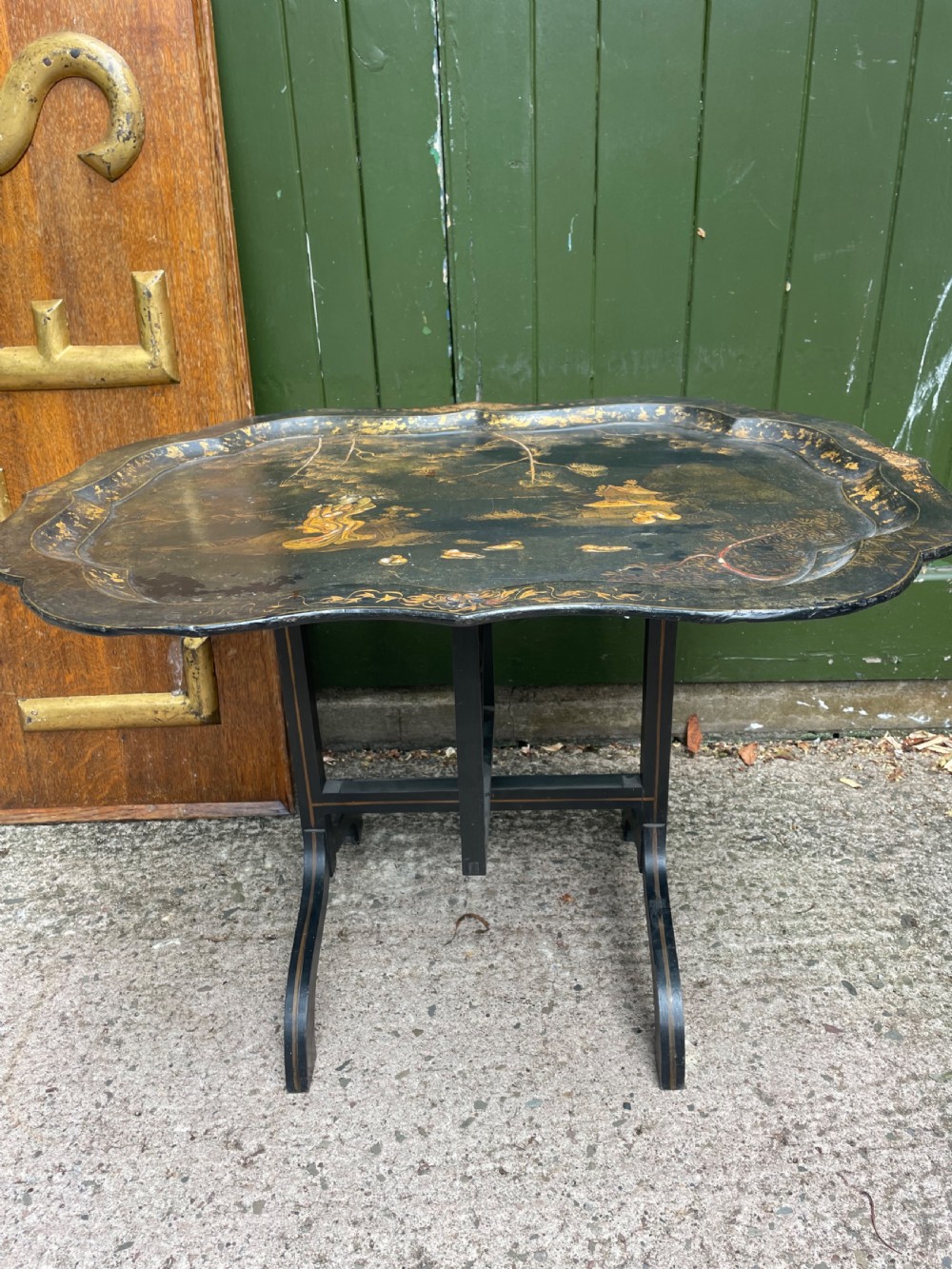 A 19th-century black lacquered papier-mache tray table featuring gilded Chinoiserie landscape decoration and scalloped edges. View VII