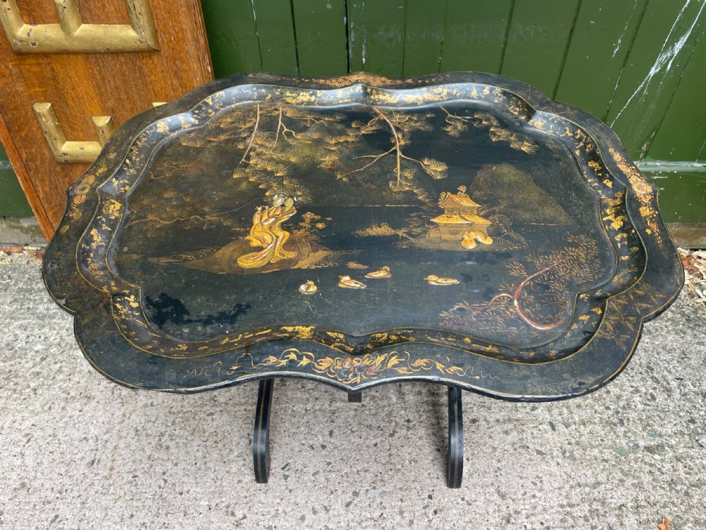 A 19th-century black lacquered papier-mache tray table featuring gilded Chinoiserie landscape decoration and scalloped edges. View VIII