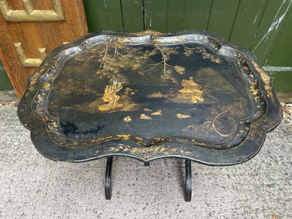 A 19th-century black lacquered papier-mache tray table featuring gilded Chinoiserie landscape decoration and scalloped edges. View XI