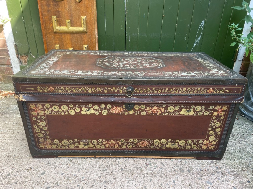 A 19th-century Chinese export leather trunk decorated with hand-painted gold and red floral motifs and brass stud borders.