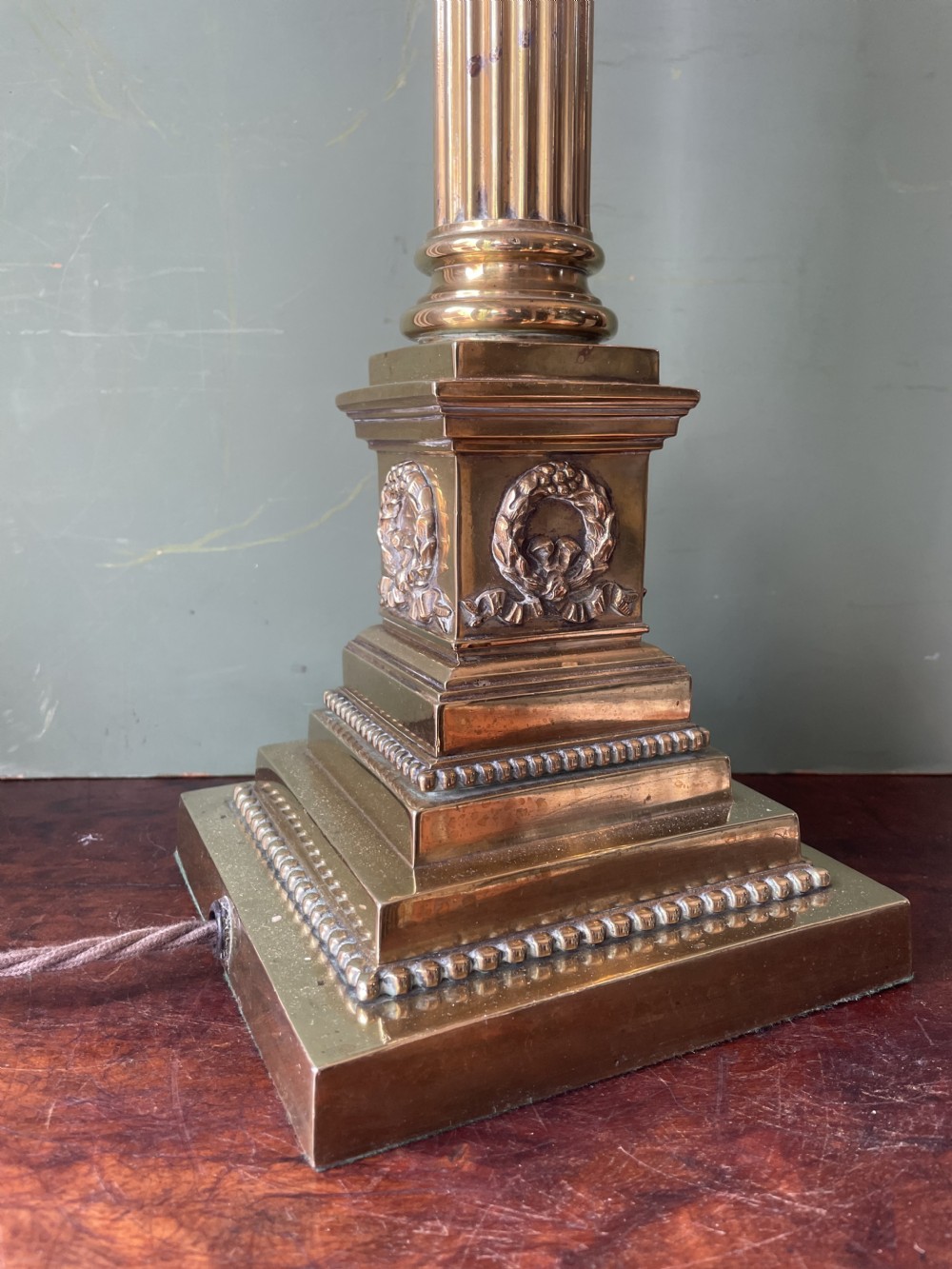 A late 19th-century brass table lamp styled as a classical fluted column with a stepped base and laurel wreath detail. View II