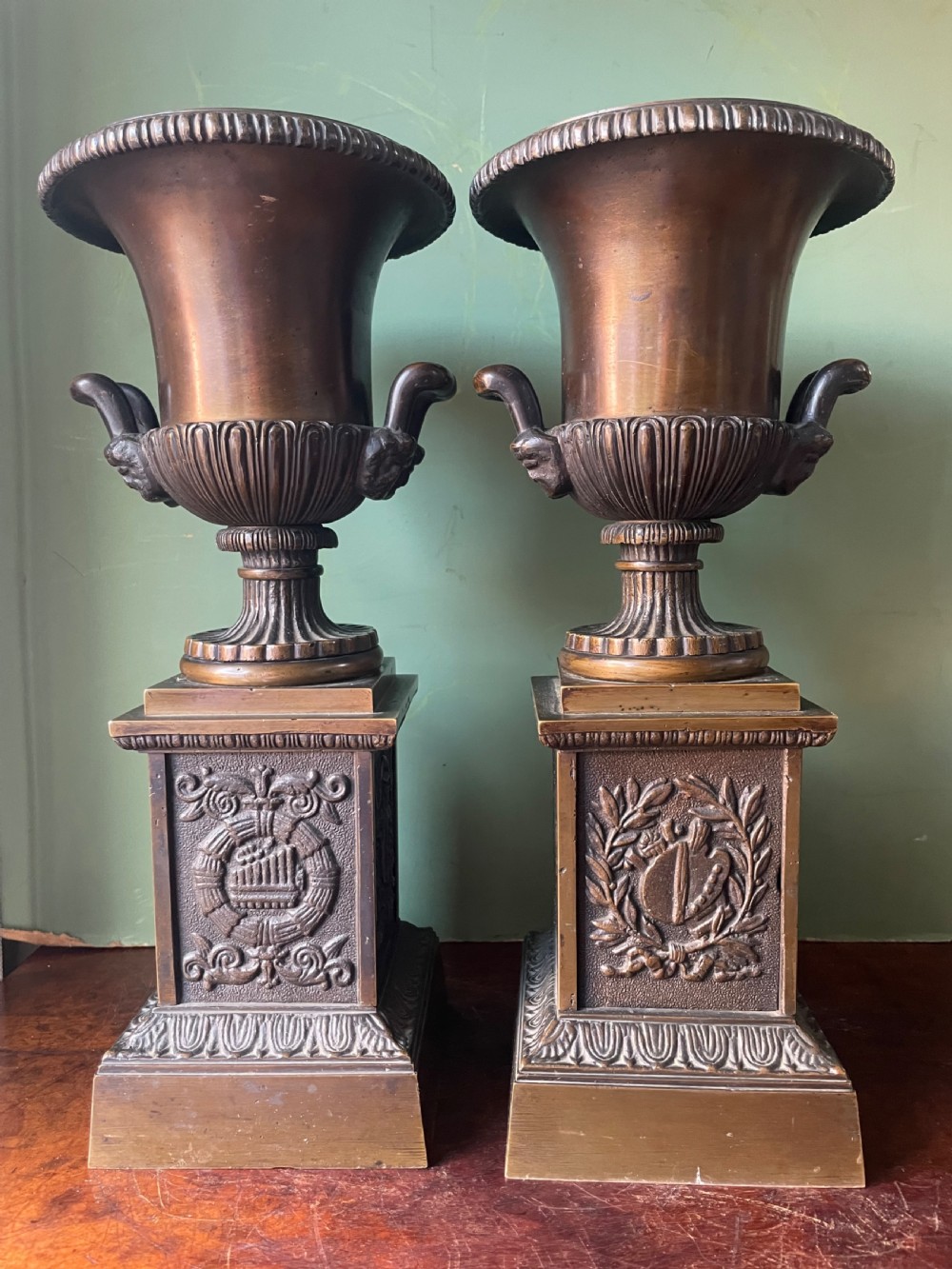 A pair of early 19th-century French Charles X bronze campana-shaped urns with fluted bodies and classical relief motifs on square plinth bases. View III