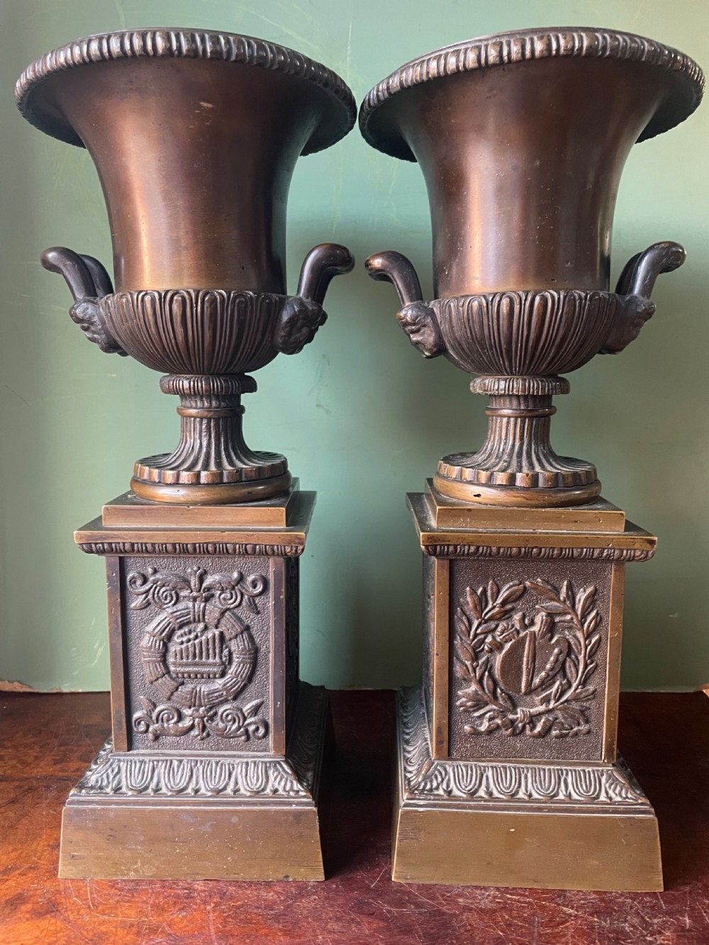 A pair of early 19th-century French Charles X bronze campana-shaped urns with fluted bodies and classical relief motifs on square plinth bases. View IV