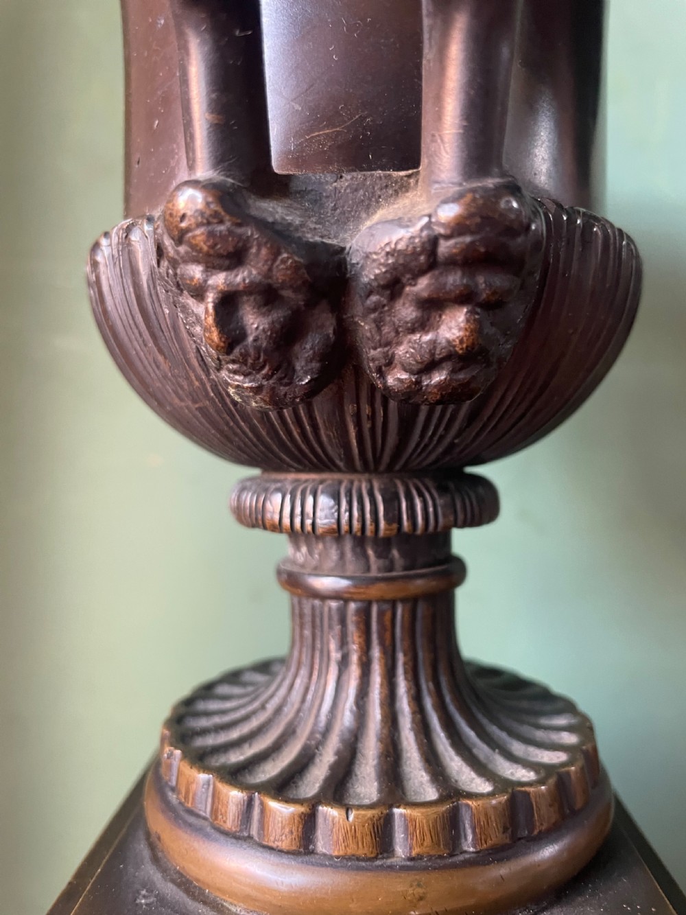 A pair of early 19th-century French Charles X bronze campana-shaped urns with fluted bodies and classical relief motifs on square plinth bases. View VI