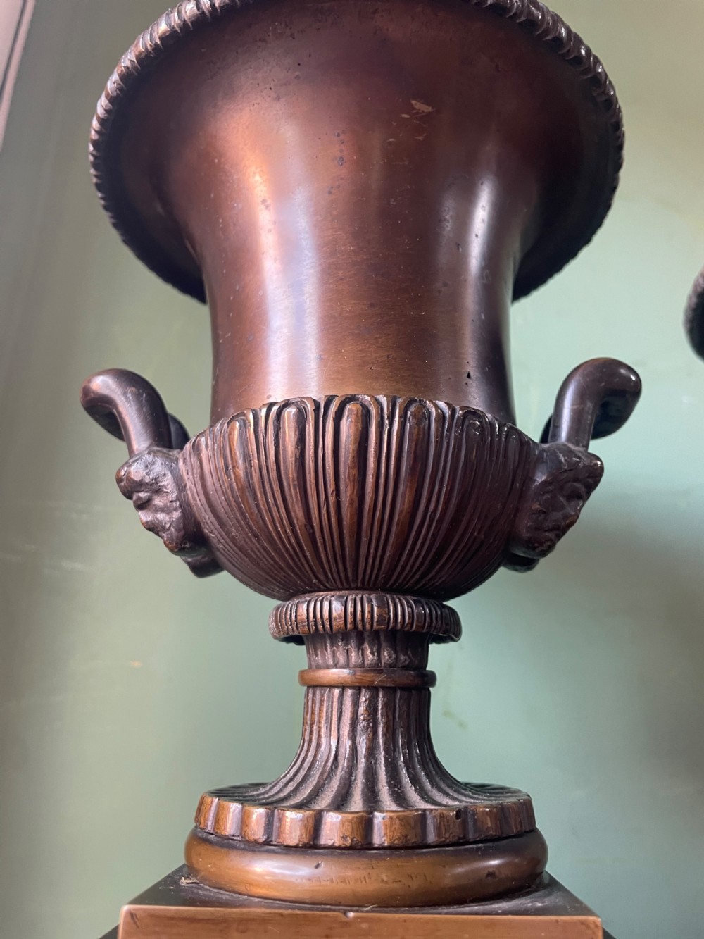A pair of early 19th-century French Charles X bronze campana-shaped urns with fluted bodies and classical relief motifs on square plinth bases. View XI