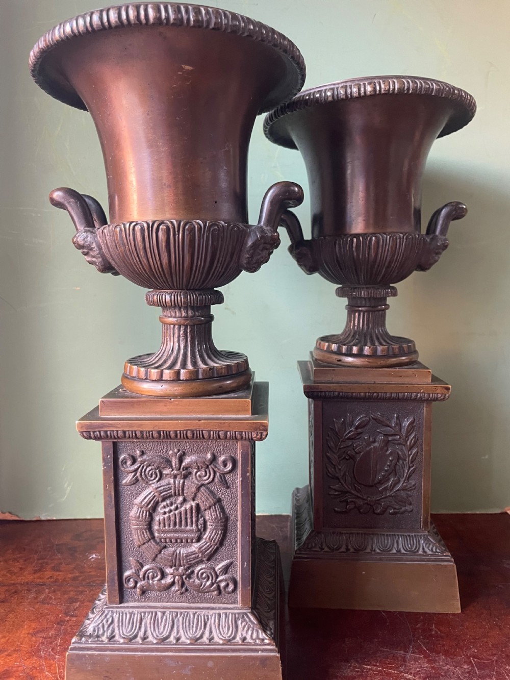 A pair of early 19th-century French Charles X bronze campana-shaped urns with fluted bodies and classical relief motifs on square plinth bases. View XII