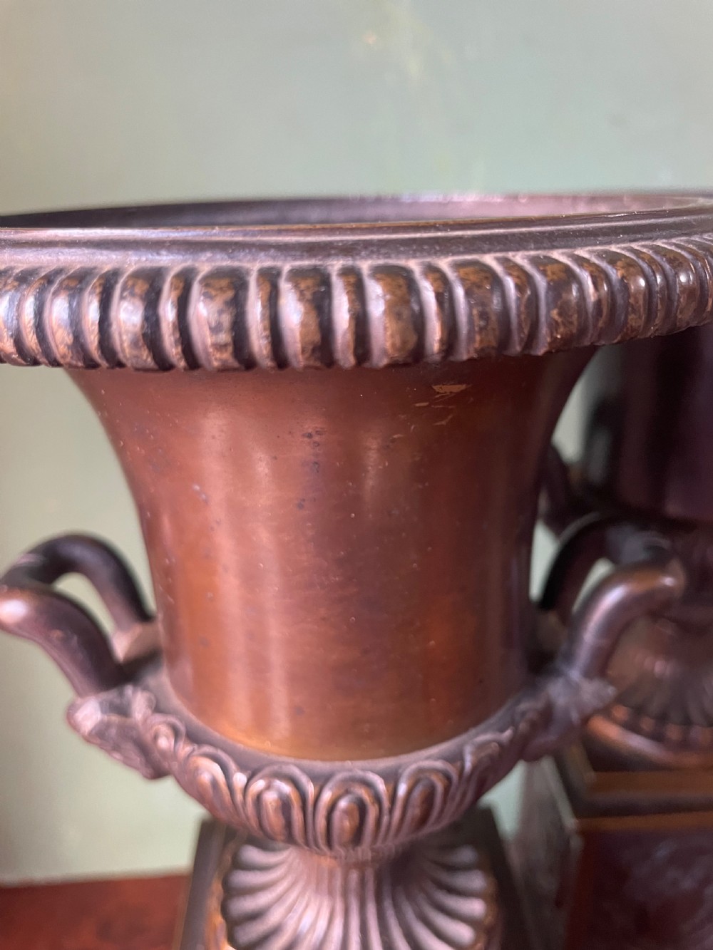 A pair of early 19th-century French Charles X bronze campana-shaped urns with fluted bodies and classical relief motifs on square plinth bases. View XIII
