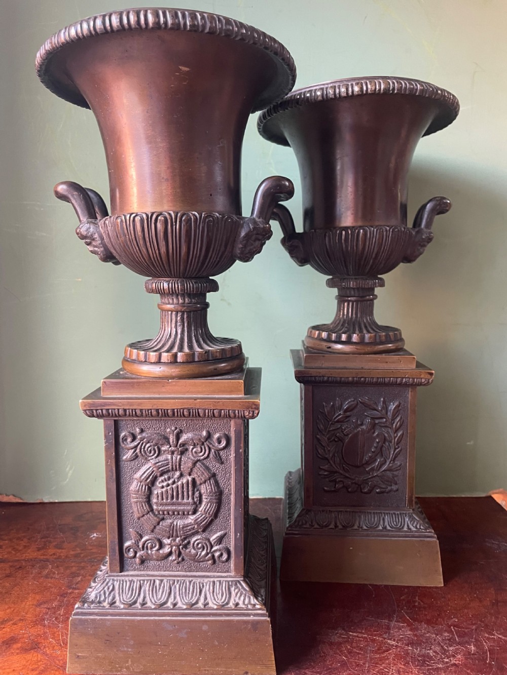 A pair of early 19th-century French Charles X bronze campana-shaped urns with fluted bodies and classical relief motifs on square plinth bases. View XIV