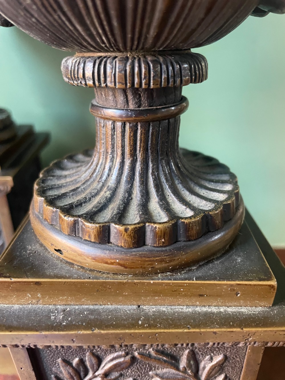 A pair of early 19th-century French Charles X bronze campana-shaped urns with fluted bodies and classical relief motifs on square plinth bases. View XV
