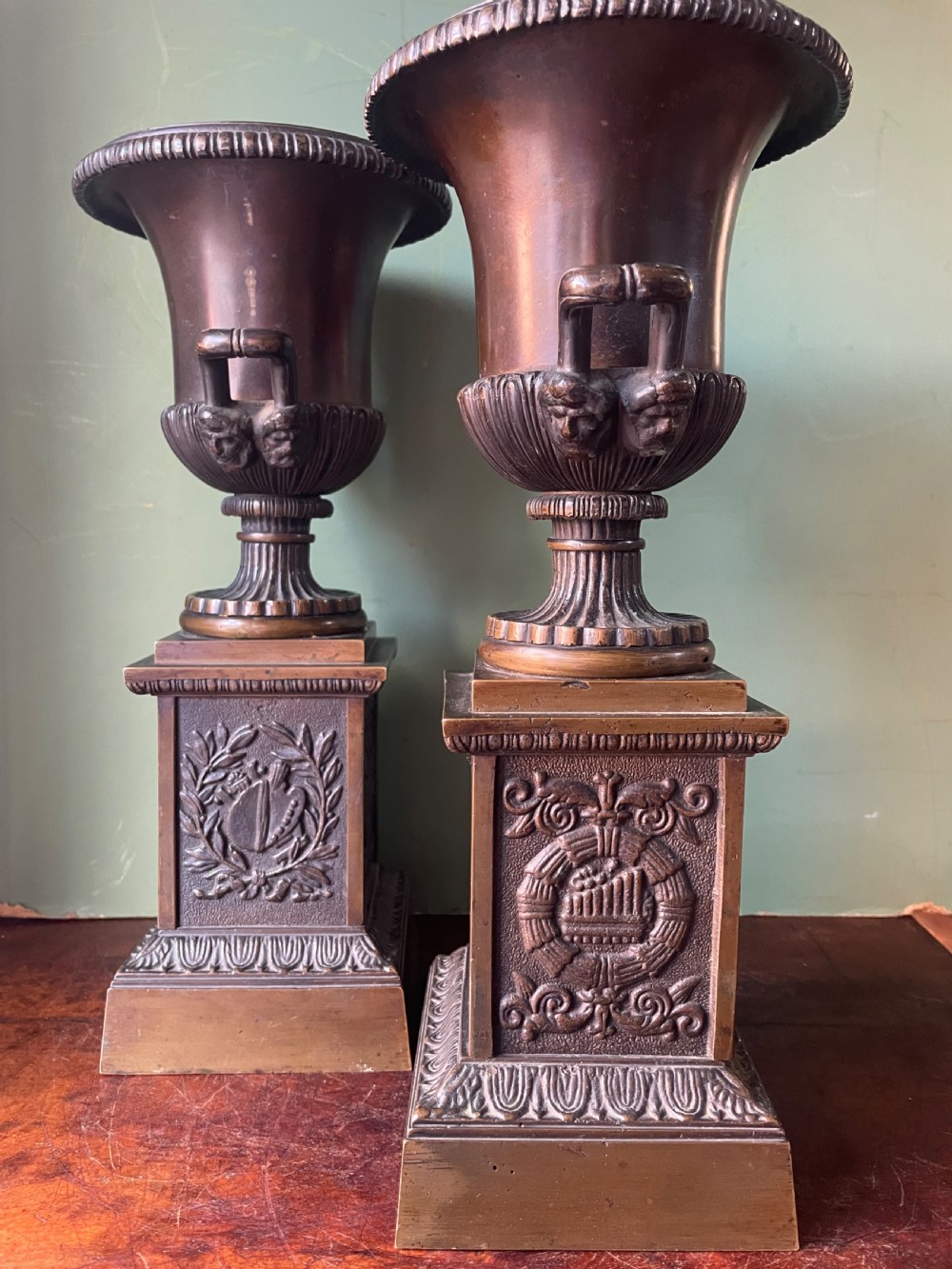 A pair of early 19th-century French Charles X bronze campana-shaped urns with fluted bodies and classical relief motifs on square plinth bases. View XVI
