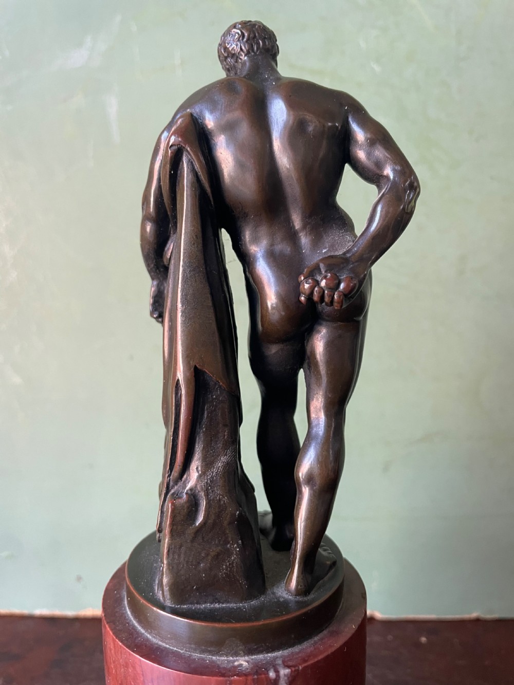 A patinated bronze study of the Farnese Hercules standing against a club draped in lion skin, mounted on a red marble plinth and black base. View VIII