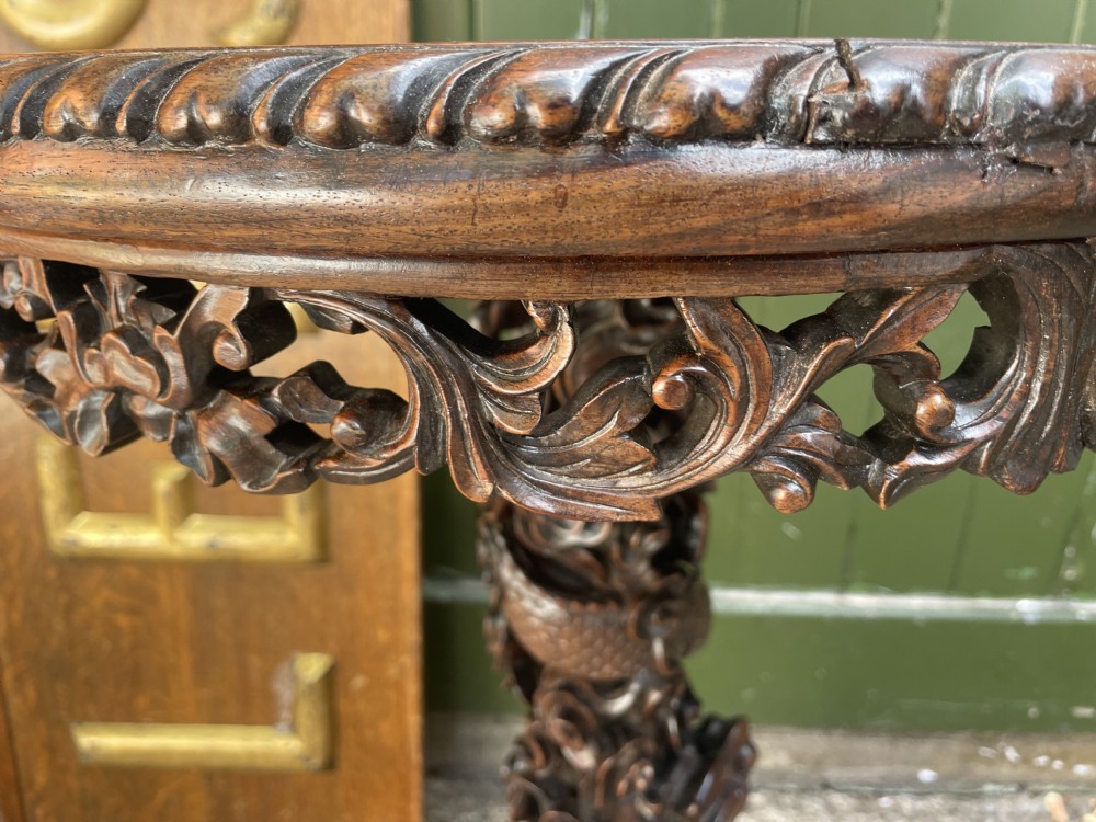A late nineteenth-century Chinese dark hardwood occasional table featuring a round inset marble top, intricately carved dragon column, and a tripod base. View IX