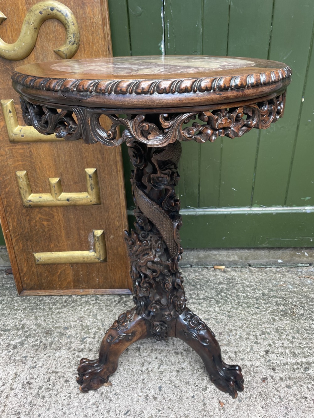 A late nineteenth-century Chinese dark hardwood occasional table featuring a round inset marble top, intricately carved dragon column, and a tripod base.