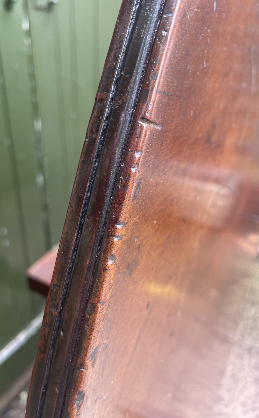 A late George III period circular mahogany tilt-top table shown in a vertical position, featuring a single-piece top and reeded tripod legs with brass castors. View V