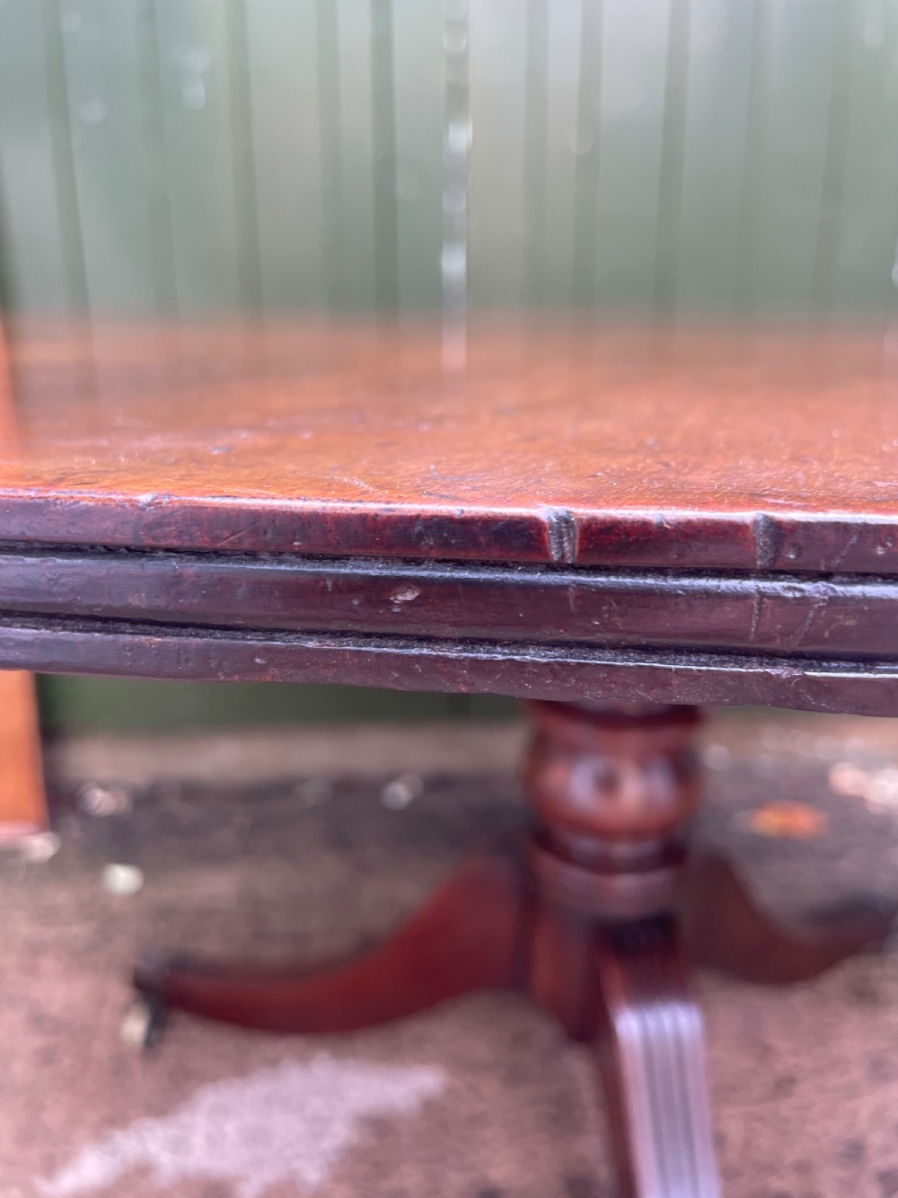 A late George III period circular mahogany tilt-top table shown in a vertical position, featuring a single-piece top and reeded tripod legs with brass castors. View XVIII