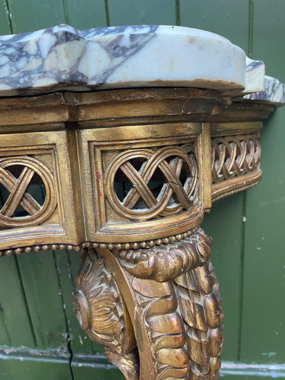 A 19th-century French giltwood console table featuring a serpentine variegated marble top, pierced lattice frieze, and carved urn stretcher. View VI