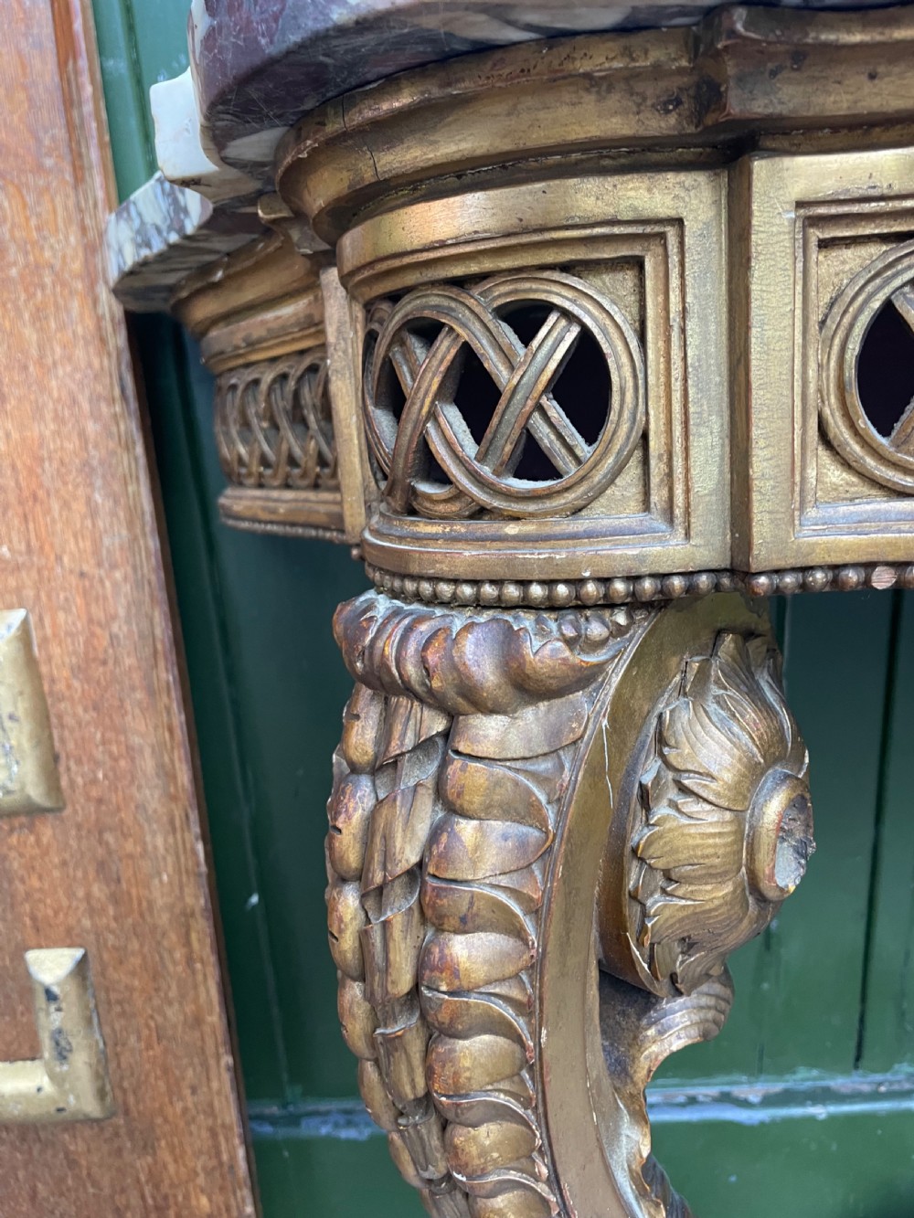 A 19th-century French giltwood console table featuring a serpentine variegated marble top, pierced lattice frieze, and carved urn stretcher. View XI