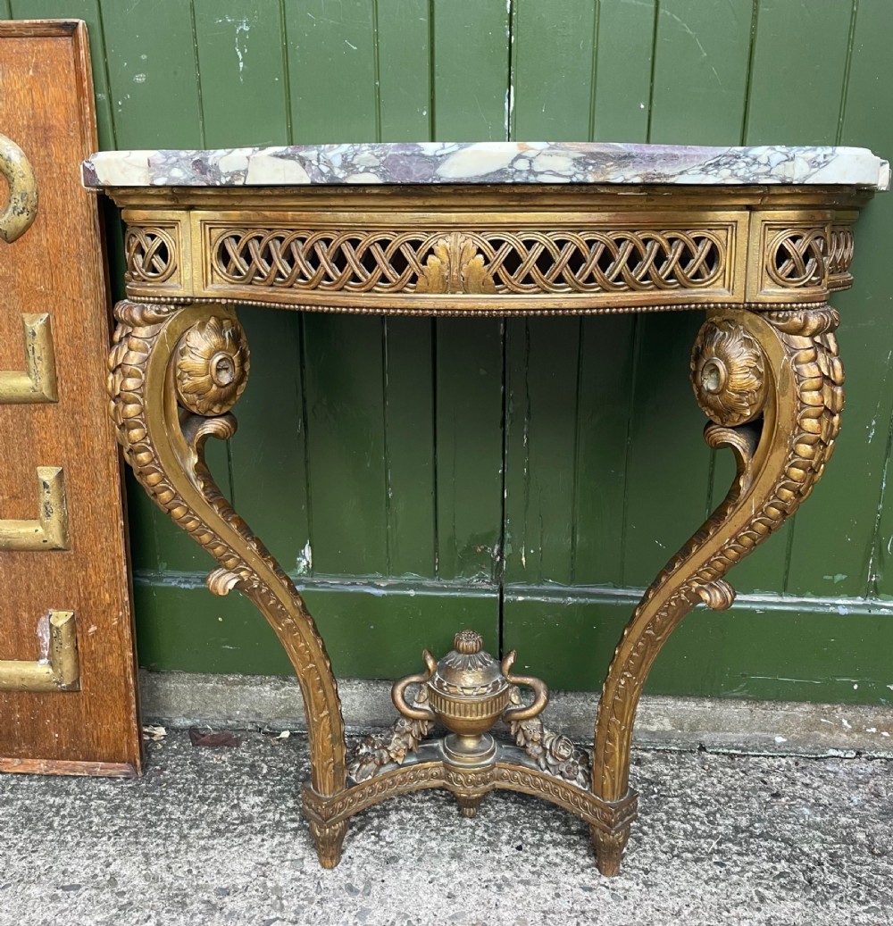 A 19th-century French giltwood console table featuring a serpentine variegated marble top, pierced lattice frieze, and carved urn stretcher. View XVII