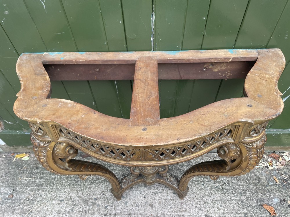 A 19th-century French giltwood console table featuring a serpentine variegated marble top, pierced lattice frieze, and carved urn stretcher. View XXI