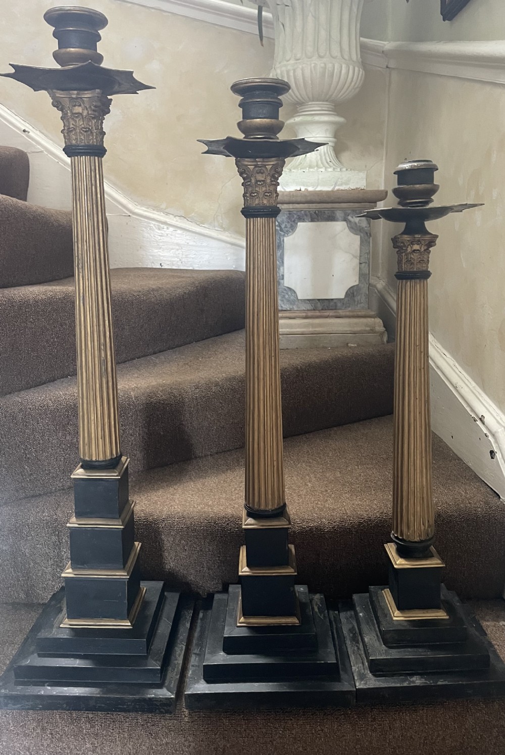 A set of three tall 19th-century graduated candlesticks featuring fluted gold-toned Corinthian columns on black stepped bases. View VI
