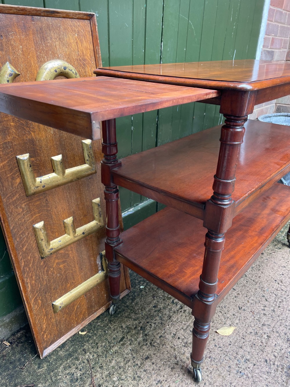 A three-tier George IV mahogany buffet table featuring turned column supports and brass castors. View V