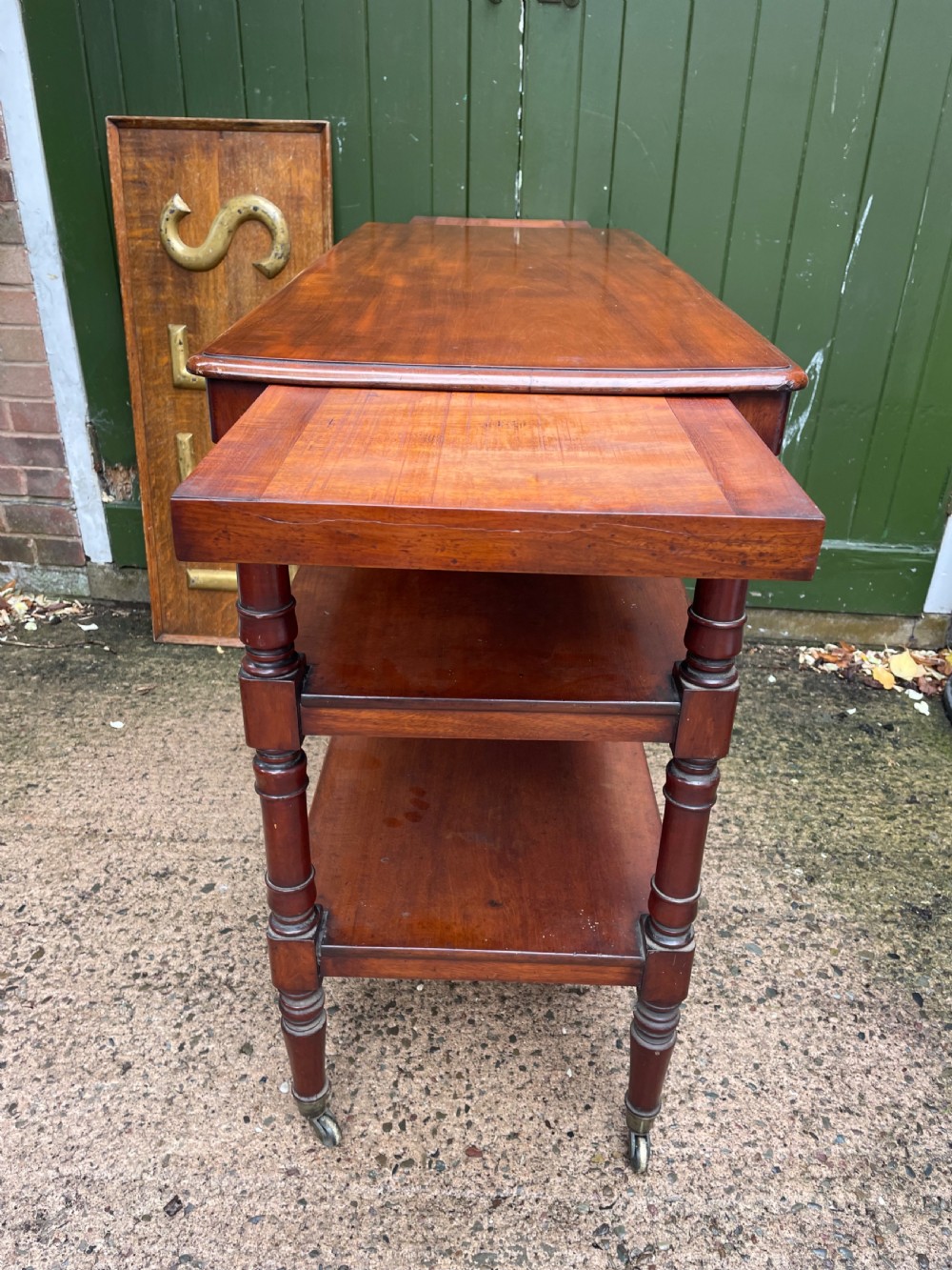 A three-tier George IV mahogany buffet table featuring turned column supports and brass castors. View IX