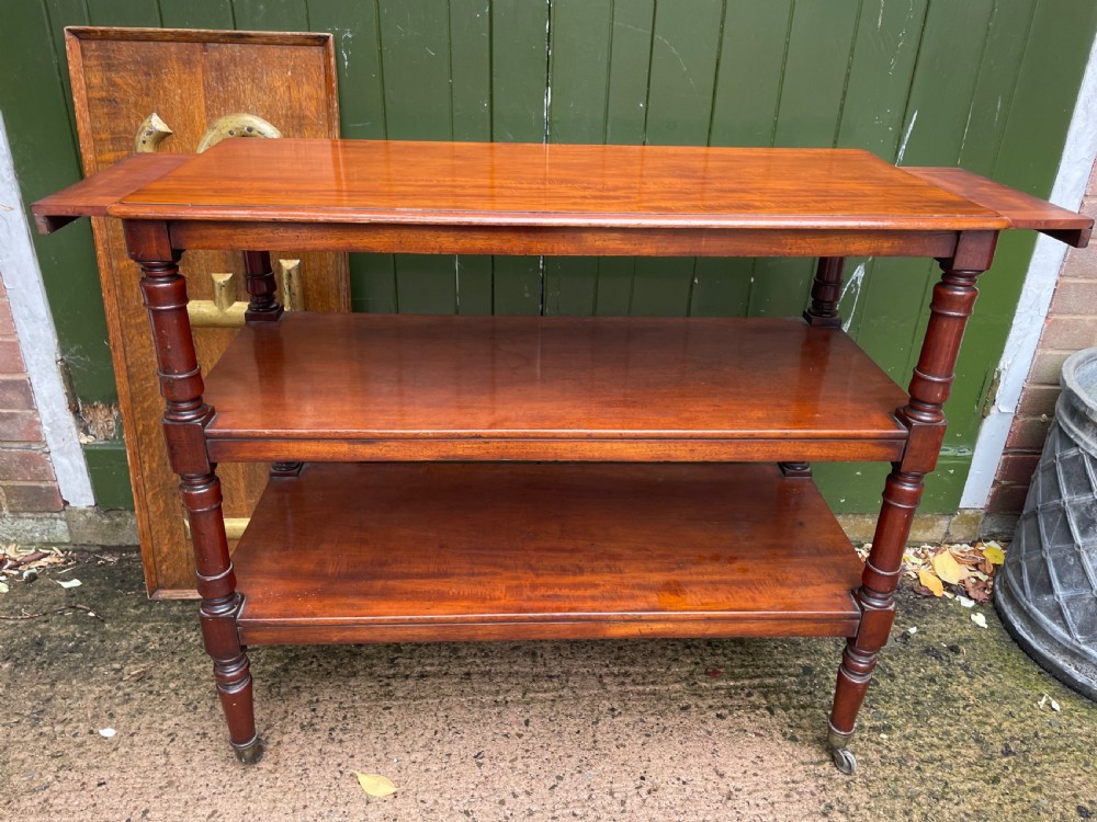 A three-tier George IV mahogany buffet table featuring turned column supports and brass castors. View XII