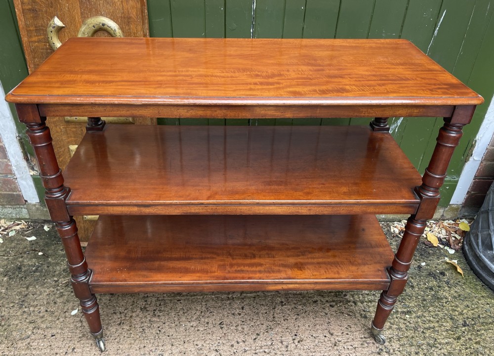 A three-tier George IV mahogany buffet table featuring turned column supports and brass castors. View XVI