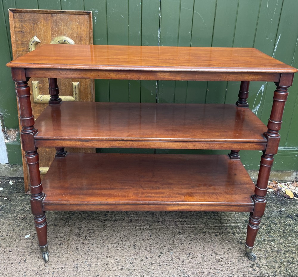 A three-tier George IV mahogany buffet table featuring turned column supports and brass castors. View XVII