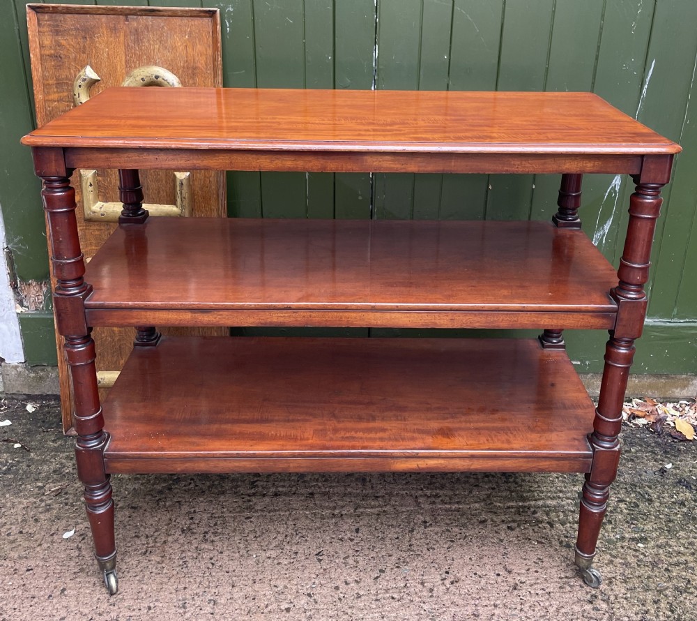 A three-tier George IV mahogany buffet table featuring turned column supports and brass castors.