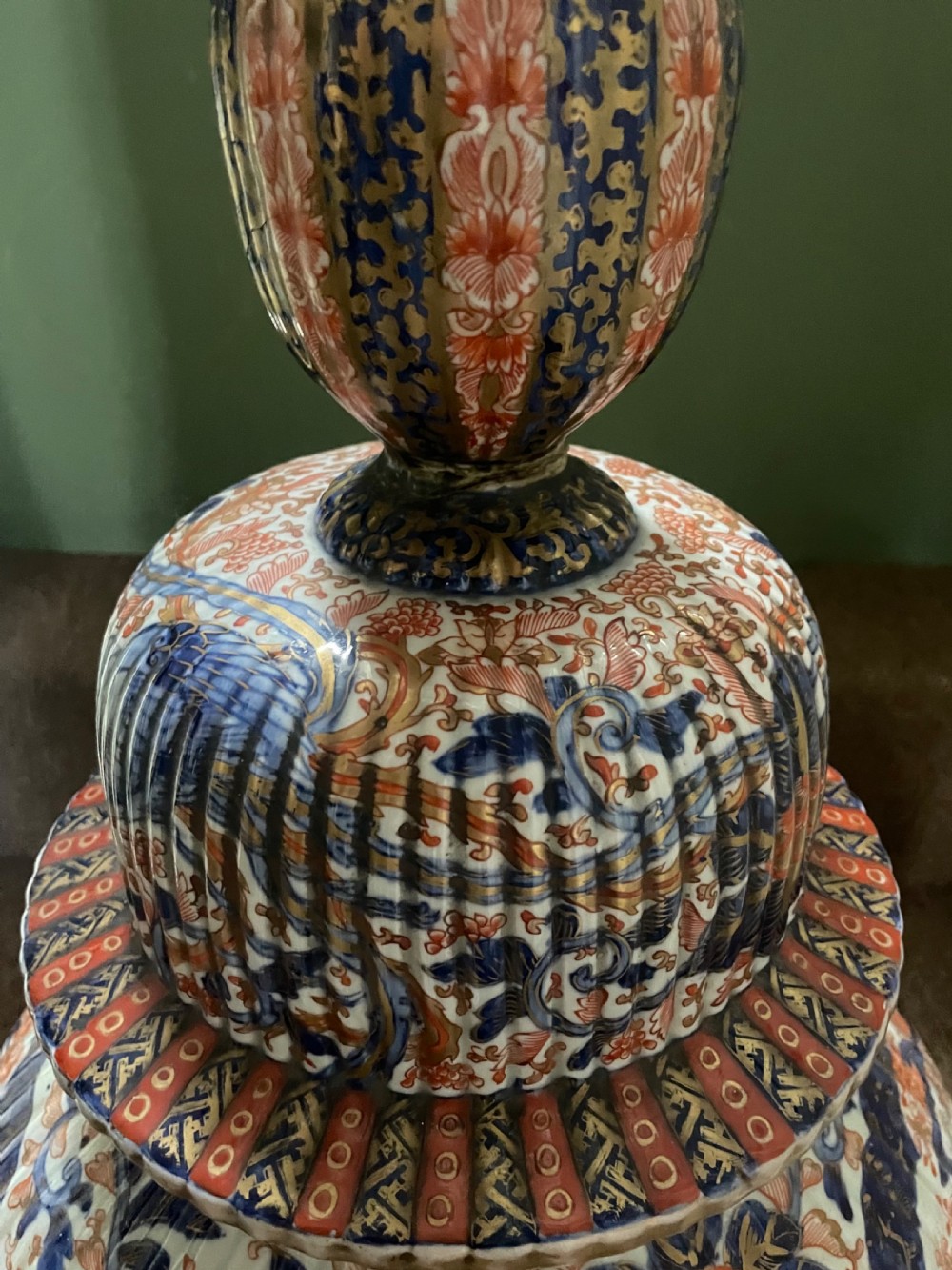 A large Japanese Meiji period porcelain covered vase featuring fluted sides and painted in underglaze blue and iron-red Imari patterns with floral motifs. View X