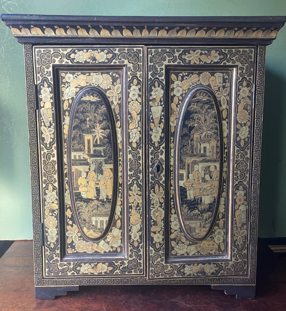 A mid-nineteenth century Chinese export black lacquer table cabinet featuring two doors decorated with gilded figural landscapes, floral borders, and geometric motifs.