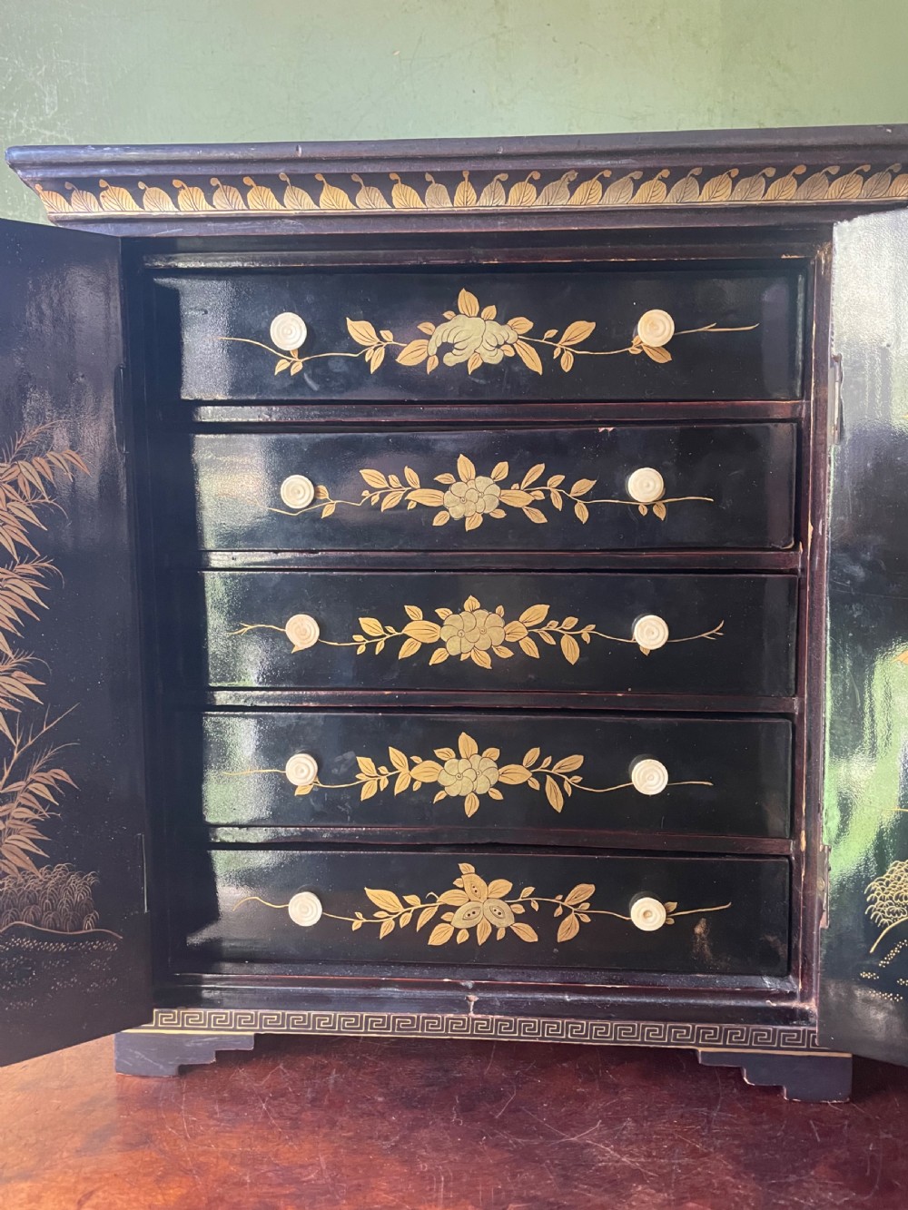 A mid-nineteenth century Chinese export black lacquer table cabinet featuring two doors decorated with gilded figural landscapes, floral borders, and geometric motifs. View V