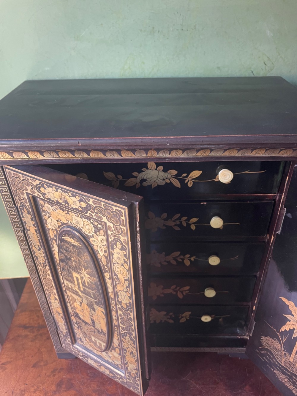 A mid-nineteenth century Chinese export black lacquer table cabinet featuring two doors decorated with gilded figural landscapes, floral borders, and geometric motifs. View IX